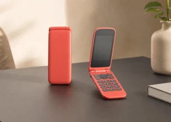 Czerwony minimalistyczny telefon z klapką z fizyczną klawiaturą na jasnym biurku