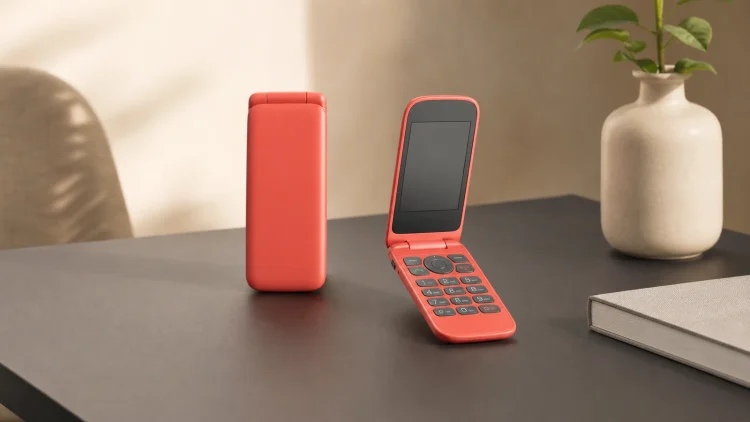 Czerwony minimalistyczny telefon z klapką z fizyczną klawiaturą na jasnym biurku