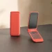 Czerwony minimalistyczny telefon z klapką z fizyczną klawiaturą na jasnym biurku