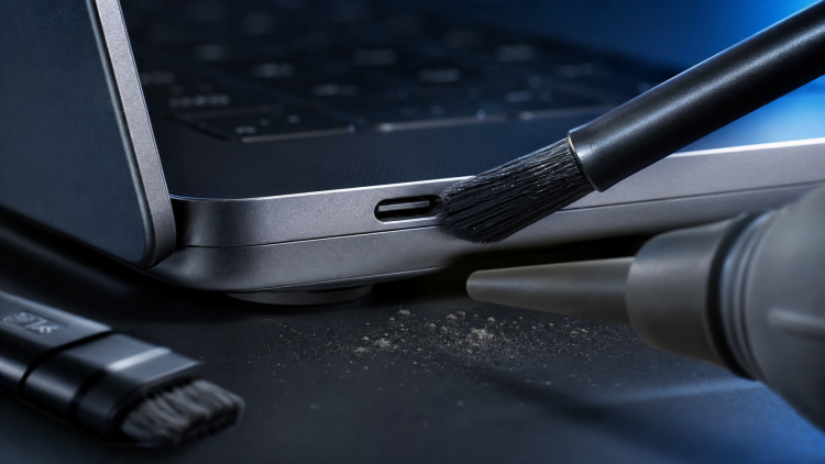 Port USB-C laptopa czyszczony miękką szczoteczką i sprężonym powietrzem