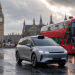Autonomiczna taksówka z czujnikami jedzie ulicą Londynu obok czerwonego autobusu
