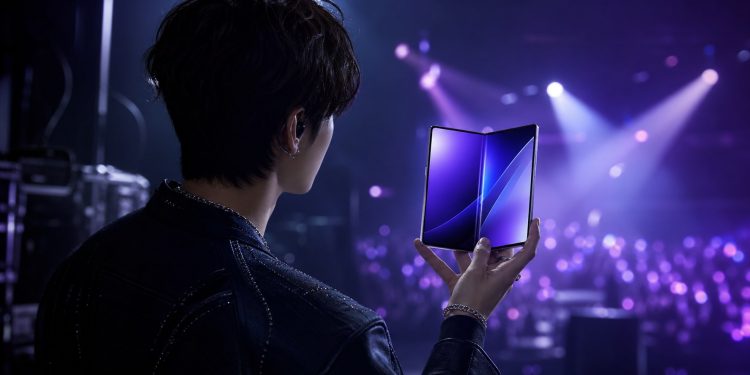 Koncepcyjna sylwetka artysty K-pop prezentującego składany smartfon na scenie